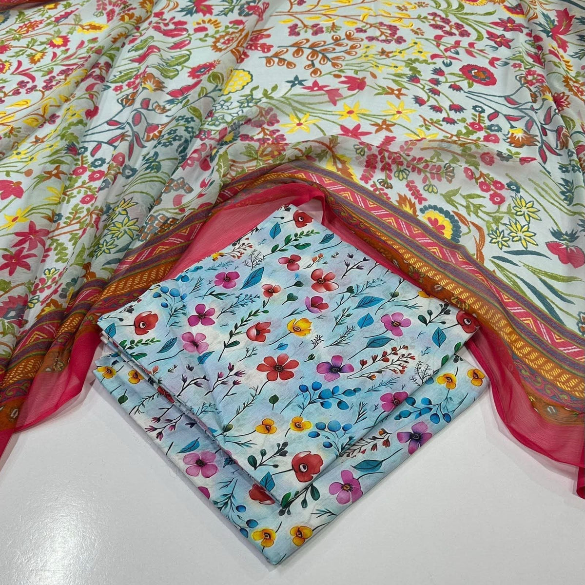 lawn 3 piece suit featuring a light blue base with a multicolor floral print and a pink border with gold detailing on dupatta