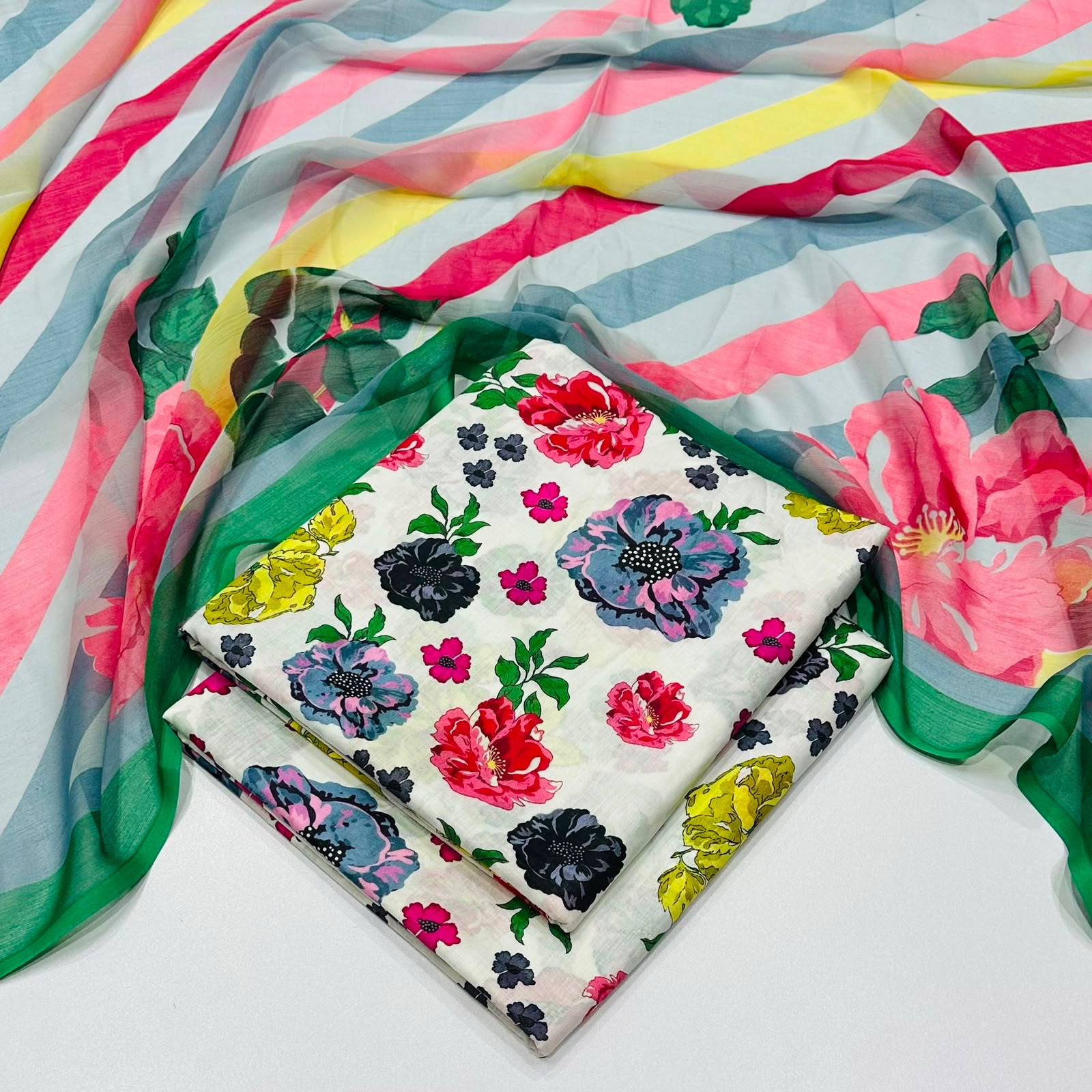 lawn 3 piece suit in white base printed with colorful floral motifs draped over a sheer striped scarf 