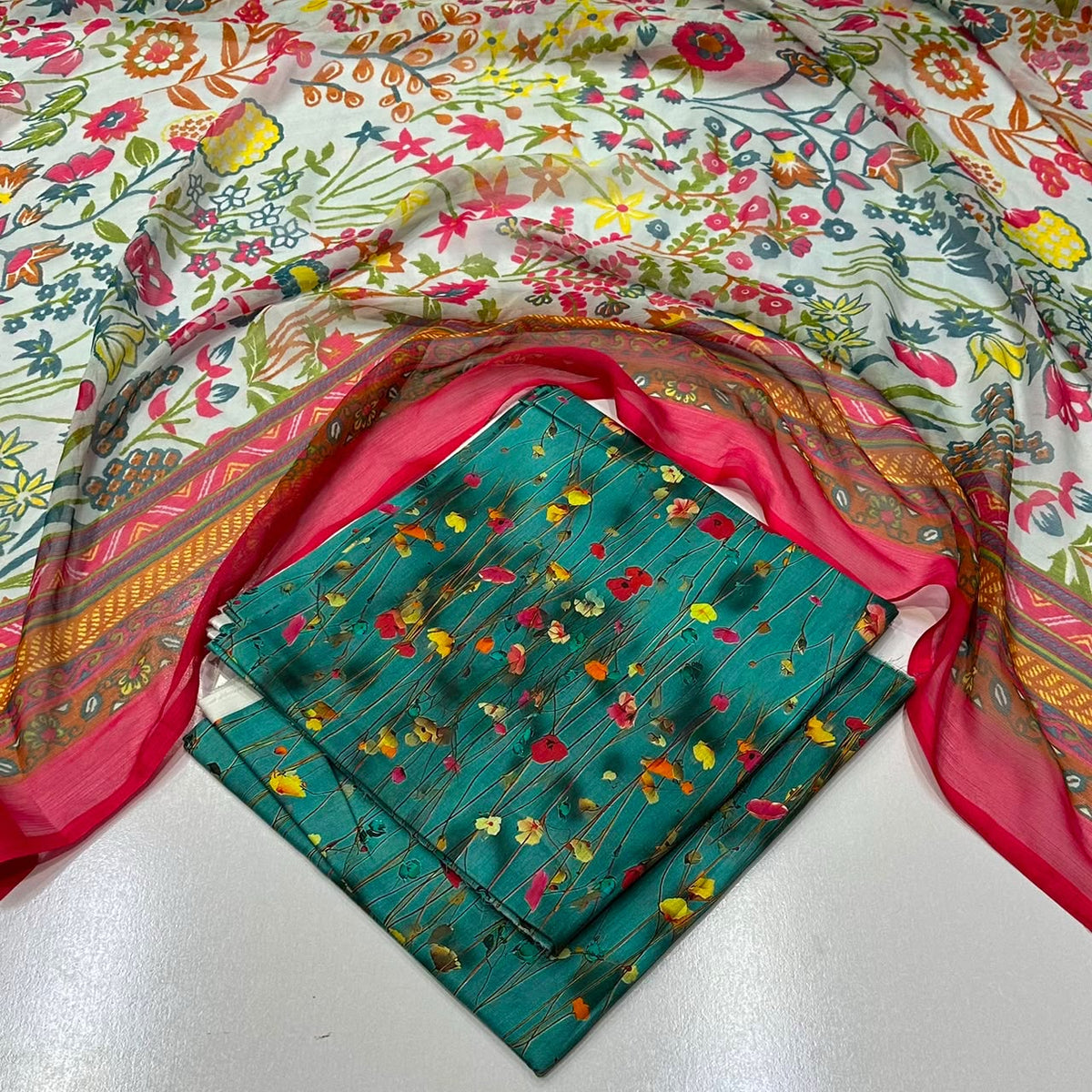 lawn 3 piece suit in teal  with a small multicolor floral  surrounded by a bright pink dupatta 