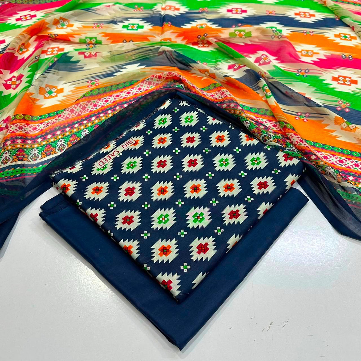 lawn 3 piece suit in navy blue fabric with a white, red, and green geometric patterned 